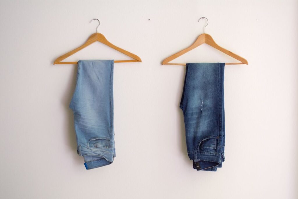 two pairs of jeans hanging on hangers