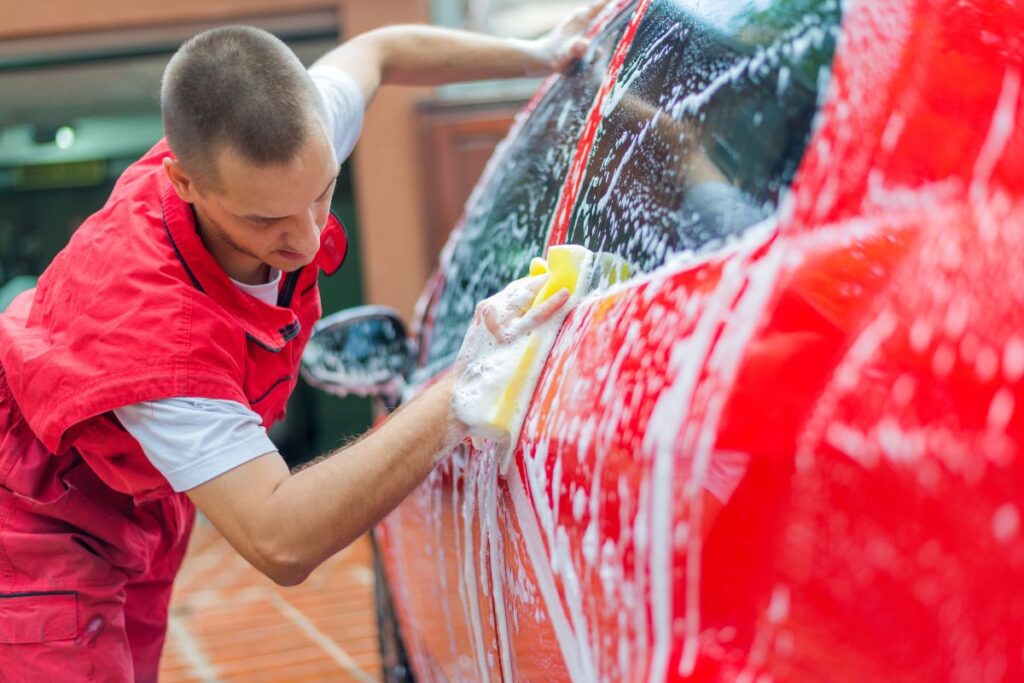 a teenage boy washing a car